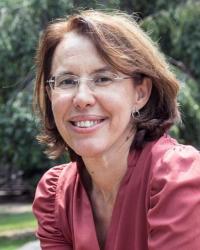 A headshot of a woman in glasses wearing a pink blouse